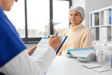 Wall Mural - medicine, health and vaccination concept - close up of doctor with clipboard and senior woman at hospital