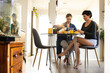 © Wavebreak Media - Mid adult caucasian lesbian couple having breakfast at dining table while sitting on chairs at home