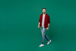 Full body young happy smiling caucasian man he 20s wearing red shirt grey t-shirt walking going strolling look camera isolated on plain dark green background studio portrait. People lifestyle concept.