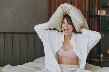 Wall Mural - Young woman wear white shirt pajama she lying in bed sad tired woman cover ears from neighbours noise snoring scream spend time in bedroom lounge home in own room hotel wake up Real estate concept