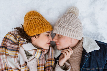 Canvas Print - people, love and leisure concept - happy smiling couple lying on snow in winter