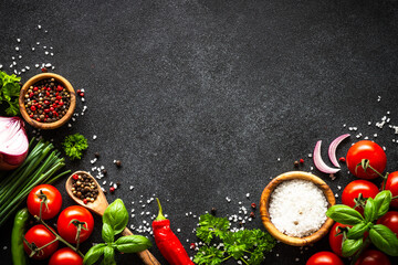 Wall Mural - Food background on black stone table. Fresh vegetables, herbs and spices. Ingredients for cooking with copy space.