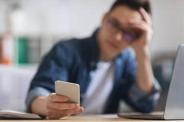Poster - Young Male Employee Using Modern Smartphone While Sitting At Desk In Office