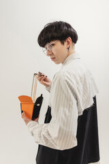 Wall Mural - Portrait of stylish young man eating necklaces like noodles, posing isolated over grey studio background. Flyer