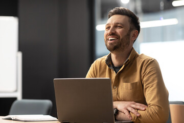 Poster - Cheerful Office Worker Man Working On Laptop Computer At Workplace