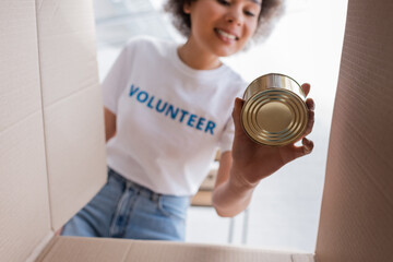 Sticker - bottom view of african american volunteer holding tin near carton box.