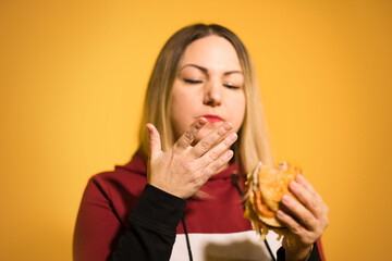 A hungry woman is biting a big tasty burger