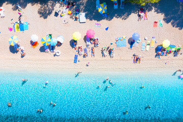 Wall Mural - Aerial view on beach, pepole and umbrellas. Vacation and adventure. Beach and blue water. Top view from drone at beach and azure sea. View on the coast from drone.