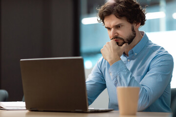 Poster - Focused mature businessman sitting at desk, working with laptop computer at modern office, copy space