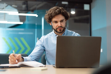 Poster - Serious mature businessman working on laptop, writing down important information at office, free space