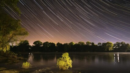Wall Mural - Star Lines Move In Sky. Star Trails On Night Sky Background. Amazing Starry Effects. 4k Timelapse Night Sky Above River. From Dusk To Dawn. Night Sky Turns Into Morning. Dawn Is Coming. Time Lapse