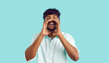 Studio Portrait Of Happy Man Holding His Hands At His Mouth And Shouting. Cheerful Young Indian Man In Shirt Speaking Loudly Or Screaming, Making Announcement And Sharing Information