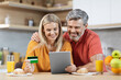 Happy couple using digital tablet and credit card at kitchen