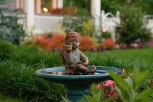 Closeup Of A Statue Of A Newborn Baby Angel In A Birdbath In A Garden