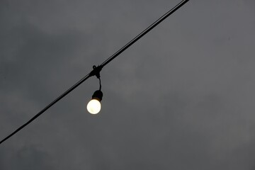 Canvas Print - Low angle shot of a light bulb hanging on a wire in the street