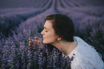 Wall Mural - Young beautiful woman in white dress enjoying fragrance on lavender field.