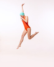 Portrait Of Young Woman In Swimming Suit And Cap Jumping Into Water Isolated Over Grey Studio Background