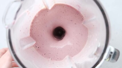 Wall Mural - Slow motion of pink berry smoothie preparing in blender, top view