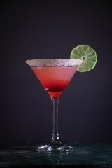 Sticker - Vertical shot of a glass of cocktail with a lime slice on a table