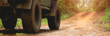 Part Of An Off-road Vehicle On A Dirt Road With Warm Light. Adventure Concept.Tire Off-road On Mud