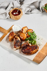 Poster - Roasted chicken with spices and herbs on wooden plate. Traditional caucasian food - chicken tabaka. Grilled chicken with bread and sauce on concrete background.