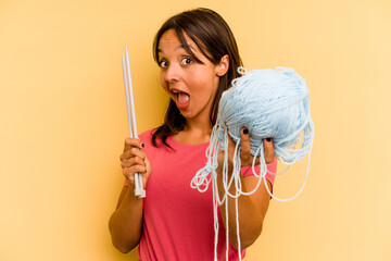 Wall Mural - Young hispanic woman holding a ball of wool isolated on yellow background