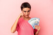 © Asier - Young caucasian woman holding banknotes isolated on pink background pointing temple with finger, thinking, focused on a task.