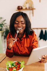 Wall Mural - Beautiful young woman eating salad in the kitchen in the morning. Healthy food. Close up. Portrait shot