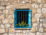 Fototapeta  - Square open window with blue iron bars in a stone house..copy space