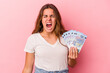 © Asier - Young caucasian woman holding bills isolated on pink background  screaming very angry and aggressive.