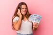 © Asier - Young caucasian woman holding bills isolated on pink background  covering ears with hands.