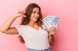 © Asier - Young caucasian woman holding bills isolated on pink background  feels proud and self confident, example to follow.