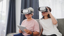 Metaverse And Virtual Reality Concept, Asian Woman And Asian Elderly Woman Wearing VR Glasses Watching Streaming From Tablet. Fun Mood.