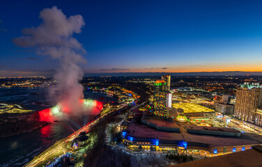 Wall Mural - Aerial view of Horseshoe Falls winter illumination in twilight time. Niagara Falls City downtown horizon. Stunning landscape dusk to night.