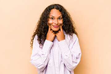 Young hispanic woman isolated on beige background doubting between two options.