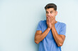 © Asier - Young caucasian man isolated on blue background thoughtful looking to a copy space covering mouth with hand.