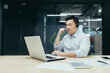 © Liubomir - Successful asian employee boss businessman working with laptop using headset for video call, man at work in office