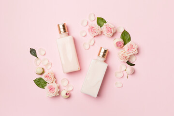 cosmetic bottles with rose flower on color background, top view