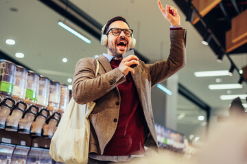 Wall Mural - Cheerful man using technology and shopping in grocery