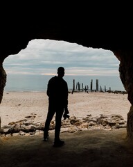 Young photographer standing on the sand and enjoying a beautiful seascape view on a cloudy day