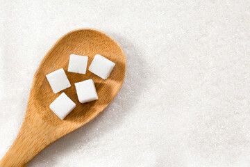 Sugar cubes on a wooden spoon close-up. Refined sugar.