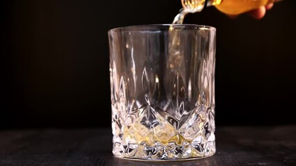 Sticker - Closeup shot of whiskey being poured into a glass on a black background