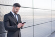 © DavidPrado - businessman using smartphone at street silver wall