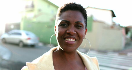 Beautiful African woman smiling at camera. Happy black ethnicity lady standing outdoors with lens-flare