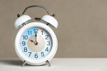 Fototapete - Ten o'clock on the alarm. A white alarm clock is on a white table. The clock hand points to 10 o'clock. Time to change to summer or winter time. Set an alarm for 10:00 or 22:00. copy space