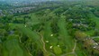 Aerial view of green golf courses with houses in the background