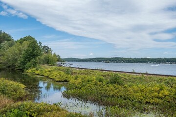 Sticker - Beautiful view of a lake with boats from a forest under the cloudy sky