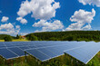 © Grispb - Sunlight traps. Solar panels in front of forest. Solar panels for cheap electricity. Country house in distance. Summer landscape with sunlight traps. Innovative power plant. Eco clean power industry