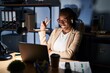 © Krakenimages.com - Beautiful black woman working at the office at night smiling with happy face winking at the camera doing victory sign. number two.