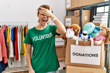 Poster - Beautiful caucasian woman wearing volunteer t shirt at donations stand smiling and laughing with hand on face covering eyes for surprise. blind concept.